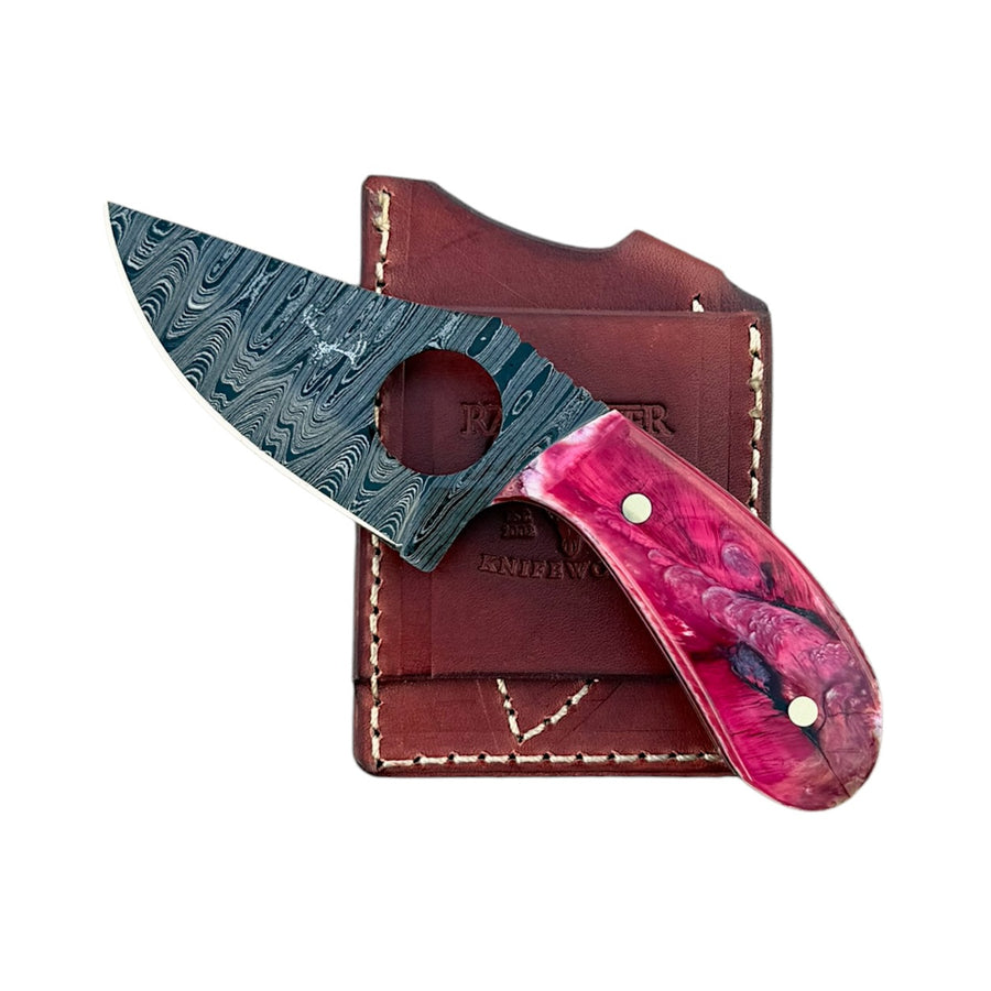 Knife with a Damascus steel blade and a vibrant pink and purple marbled handle, shown with its brown leather sheath on a white background